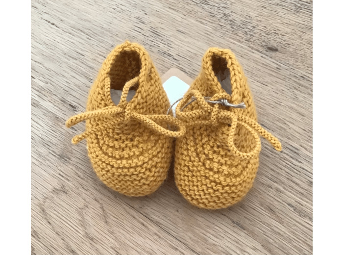 Chaussons bébé , en laine coloris moutarde, avec des petits noeuds.
