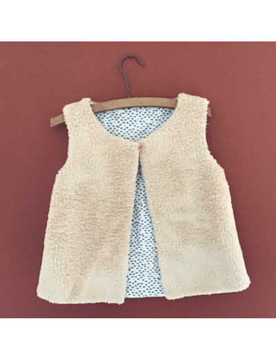 Gilet berger réversible en fausse fourrure beige et tissu coton petites touffes d herbes sur fond blanc.